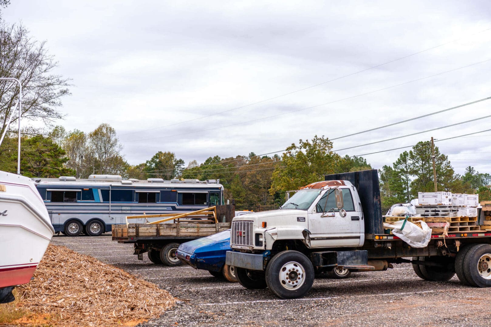 Truck and trailer parked near RV and boat.