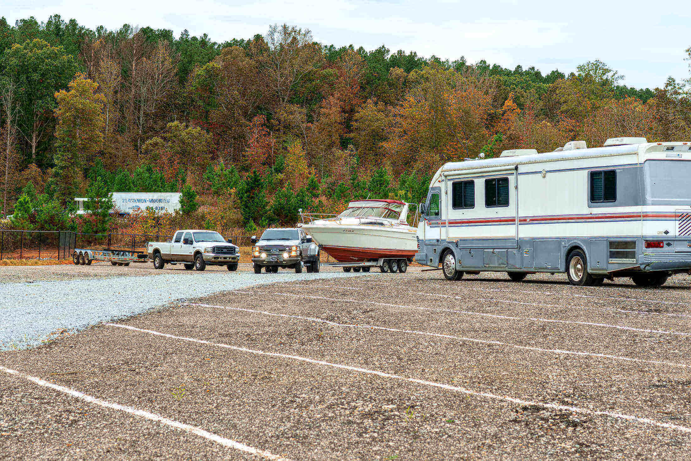 RV and vehicles near wooded area.